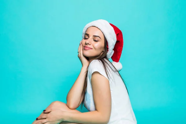 Улыбающаяся женщина портрет с рождественской шляпой сидя на полу изолированный портрет на цветном фоне — стоковое фото