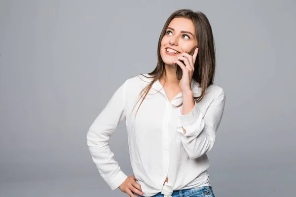 Vacker attraktiva avslappnad ung kvinna talar på sin mobiltelefon. Studio skott över grå bakgrund. — Stockfoto