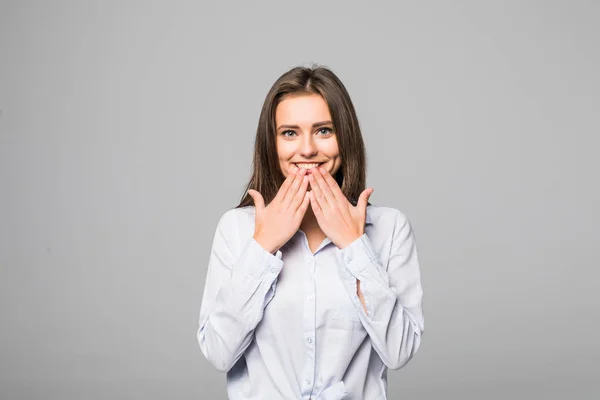 Close up Mujer joven feliz sonriendo a la cámara mientras se cubre la boca con la mano contra el fondo gris —  Fotos de Stock