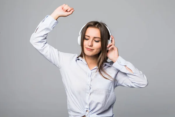 Mujer feliz con camisa escuchando música y bailando en el suelo con los ojos cerrados. Fondo gris aislado —  Fotos de Stock