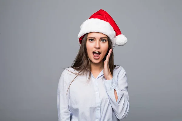 Verbaasd kerst vrouw dragen een kerstmuts glimlachend geïsoleerde over grijze achtergrond — Stockfoto