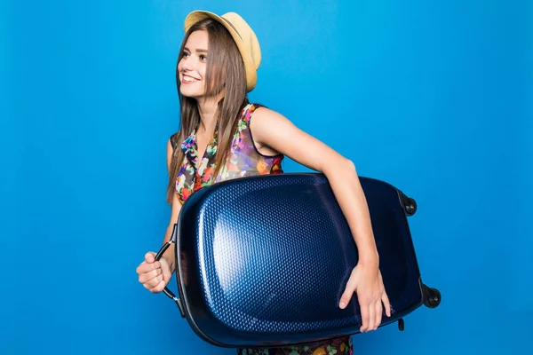 Onnellinen nuori nainen, jolla on matkalaukku, nostaa jalkansa kuin juoksija. Kesälomien aika sinisellä pohjalla . — kuvapankkivalokuva