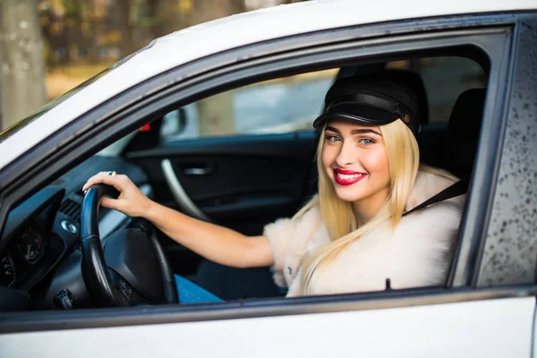 Conduciendo por la ciudad. Mujer joven sonriendo y mirando recto mientras conduce un coche — Foto de Stock