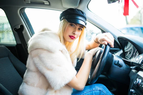 Hermosa mujer sonriente sentada en un coche nuevo. mujer manos en la rueda en el coche nuevo — Foto de Stock