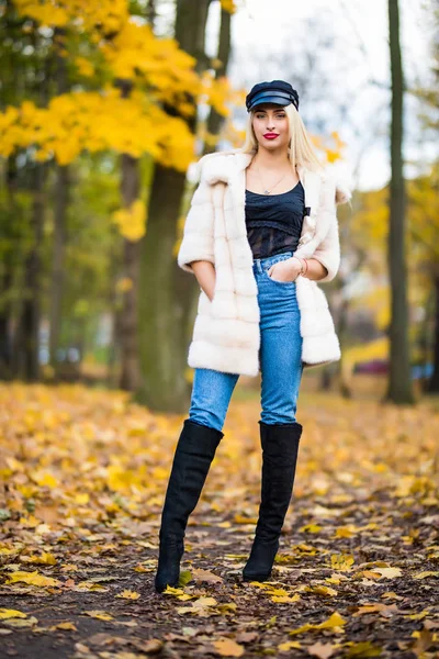 Portrait of young smiling woman with hair, dressed in coat near branches of a tree with yellow foliage for a walk in the park. Portrait of happiness. — Stock Photo, Image