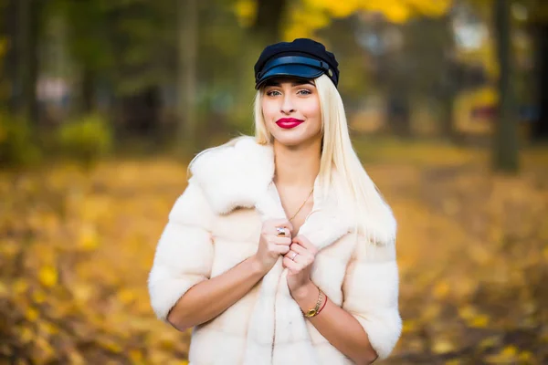 Porträtt av unga leende kvinna med hår, klädd i päls nära grenarna i ett träd med gult bladverk för en promenad i parken. Porträtt av lycka. — Stockfoto