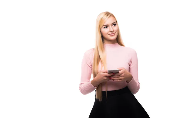 Glada blond tjej använda smartphone medan textilen meddelande med leende. Inomhus porträtt av upphetsad ung kvinna anläggning telefon — Stockfoto