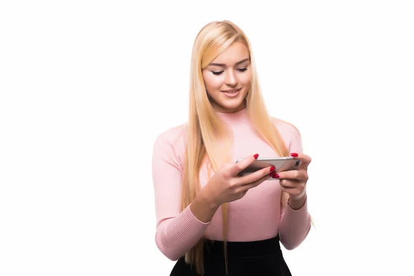 Glada blond tjej använda smartphone medan textilen meddelande med leende. Inomhus porträtt av upphetsad ung kvinna anläggning telefon — Stockfoto