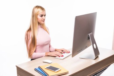 Beyaz arka plan üzerinde ofiste masa başında otururken bilgisayar kullanarak güzel mutlu işkadını