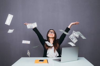 Genç güzel işkadını dizüstü bilgisayar ile ofis yerinde oturan para, yukarı atma