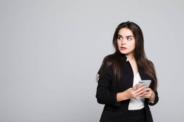 Bu cep telefonu akıllı insanlar içindir. Cep telefonu tutarak ve gri arka plan karşı dururken kamera bakıyor güzel genç iş kadını