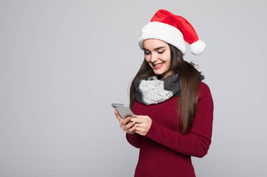 Cep telefonuyla gri arka plan üzerinde izole kırmızı Noel Baba genç esmer bir kadın portresi