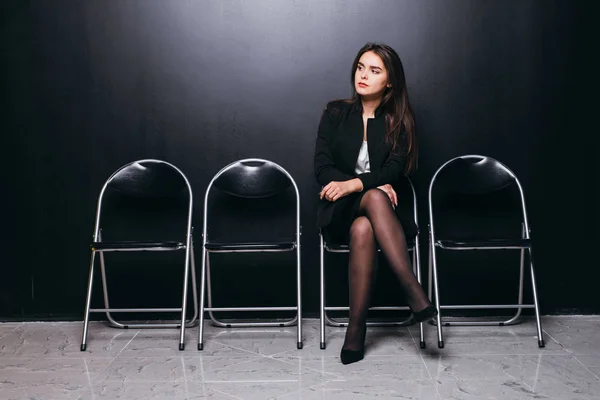 Sırada bekleyen. Siyah arka plan karşı sandalyeye oturup kendine güvenen genç iş kadını — Stok fotoğraf