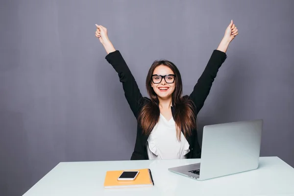 Portret van gelukkige jonge succesvolle zakenvrouw vieren iets met armen omhoog. Gelukkige vrouw zitten op kantoor en laptop kijken. Positieve emotie. — Stockfoto