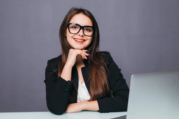 Retrato de una alegre mujer de negocios sentada a la mesa en la oficina y mirando a la cámara — Foto de Stock