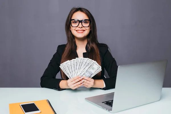 Retrato de mujer de negocios feliz con dinero en las manos en el lugar de trabajo con el ordenador portátil — Foto de Stock