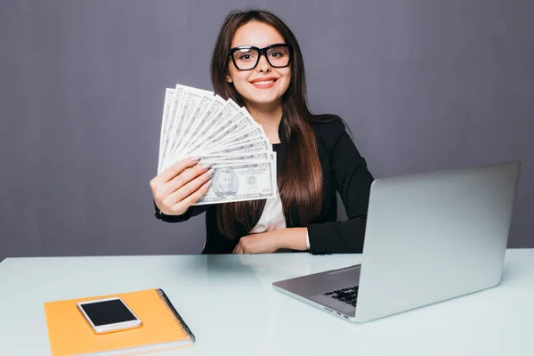 Retrato de mujer de negocios feliz con dinero en las manos en el lugar de trabajo con el ordenador portátil — Foto de Stock
