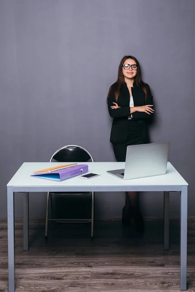 Sonriente joven dama de negocios de pie cerca del escritorio de la oficina — Foto de Stock