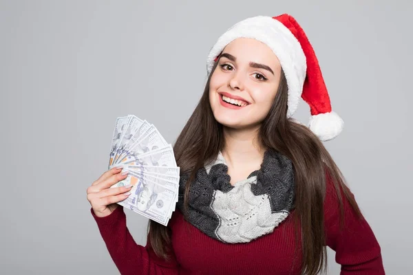 Feliz joven sonriente mujer en sombrero de santa con billetes de dólar aislados sobre fondo gris . — Foto de Stock