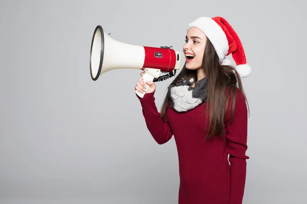 Захоплена жінка в капелюсі Санта тримає мегафон на сірому фоні — стокове фото
