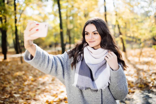 Fiatal lány vesz egy selfie a háttérben őszi park — Stock Fotó