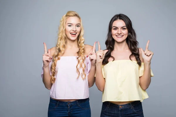 Dos amigas riéndose. Dos amigas mujeres señaladas sobre fondo blanco —  Fotos de Stock