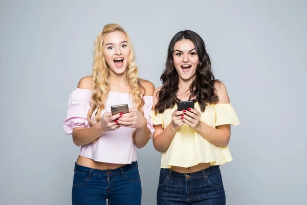 Zwei Schönheitsfreundinnen Frauen tippen Nachricht auf Telefonen auf weißem Hintergrund — Stockfoto