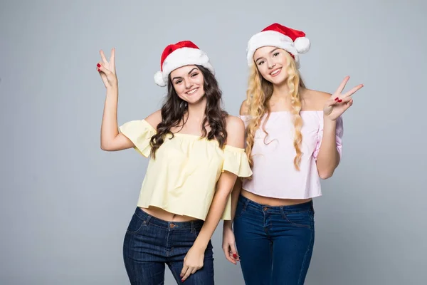 Portrait of two lovely happy women in santa hats having fun isolated over white background — Stock Photo, Image