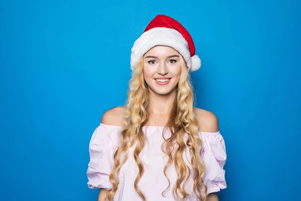Ritratto di giovane bella donna in cappello di Babbo Natale su sfondo blu — Foto Stock