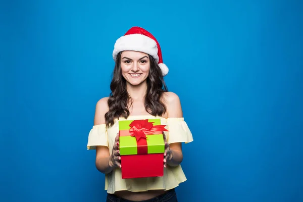 Ritratto di giovane donna in cappello di Babbo Natale con scatola regalo su sfondo blu — Foto Stock