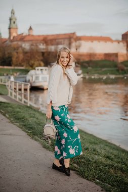 Gün batımında nehir kenarında yürüyen güzel sarışın genç kadın. Saçları rüzgarda