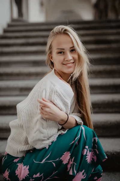Şık mutlu sarışın genç kadın merdivenlerde oturan. — Stok fotoğraf