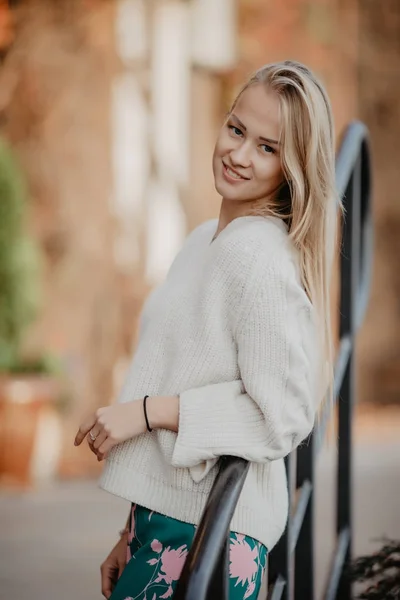 Jonge mooie Kaukasische blonde vrouw buiten in stad terug licht, leunend op de leuning. — Stockfoto