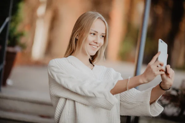 Closeup selfie-portret student van aantrekkelijk meisje in zonnebril met lange haarstijl en sneeuwwitte glimlach in stad. — Stockfoto