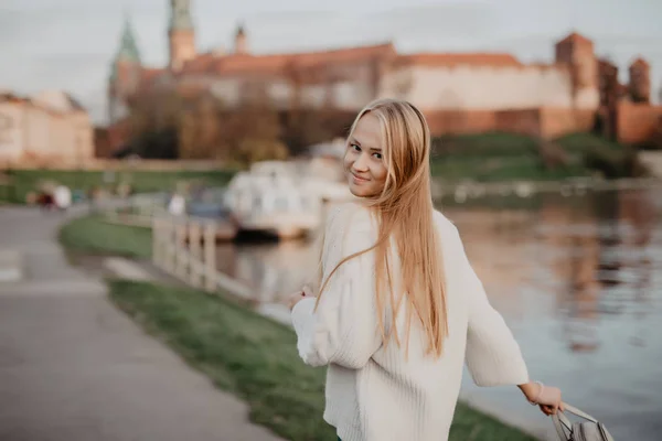 Vacker blond ung kvinna går bredvid floden vid solnedgången ha kul ler och spela på kamera — Stockfoto