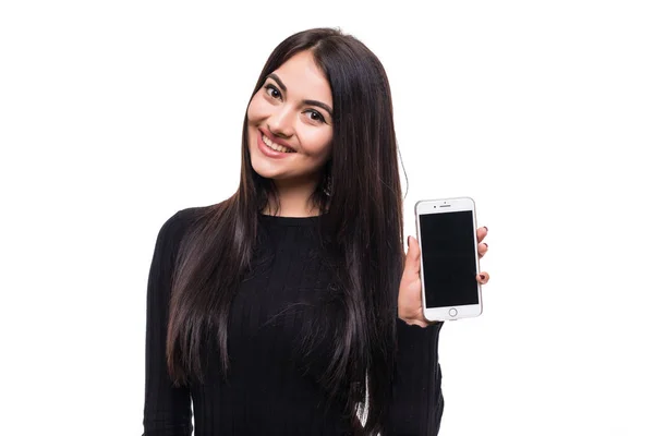 Jovem mulher feliz de pé isolado sobre parede branca olhando câmera e mostrando exibição de telefone móvel — Fotografia de Stock