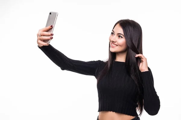 Красивая молодая счастливая женщина делает селфи на смартфоне на белом фоне — стоковое фото