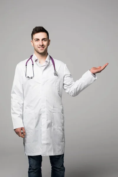 Молодой врач с открытой ладонью на белом фоне — стоковое фото