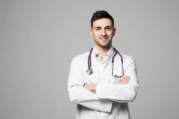 Fiatal férfi orvos sztetoszkóp, és keresztbe kezek elszigetelt fehér background — Stock Fotó
