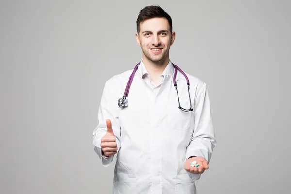 Alentador médico o médico que ofrece la mano llena de varias píldoras que muestran como gesto en gris —  Fotos de Stock