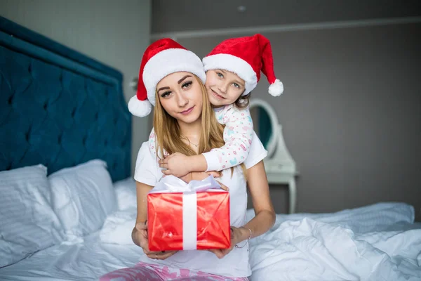 Sarılma ve hediyeler Noel sabahı yatakta vererek mutlu aile anne ve çocuk kızı domuzcuk — Stok fotoğraf