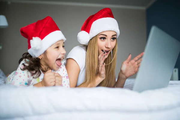 Heyecanlı ve sürpriz anne ve kızı yatakta dizüstü kullanarak Noel sabahı — Stok fotoğraf