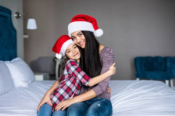 Lyckliga familjen mor och barn dotter kramas i sängen på juldagsmorgonen — Stockfoto