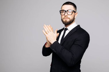 Kendine güvenen zarif yakışıklı genç adam güzel bir takım elbise giyen bir stüdyoda gri bir arka plan önünde duran