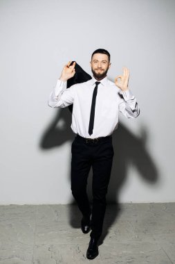 Mutlu işadamı adam iyi jest gri arka plan üzerinde sinek ceket işareti olan