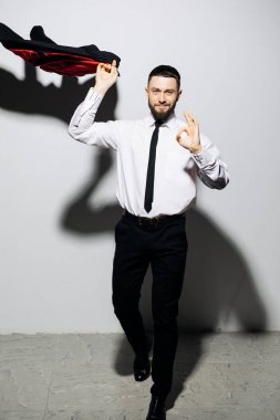 Mutlu işadamı adam iyi jest gri arka plan üzerinde sinek ceket işareti olan