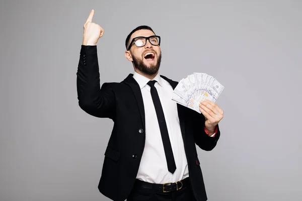 Imagen del hombre gritando en traje oficial parado aislado sobre fondo gris de la pared. Mirando a un lado sosteniendo el dinero tienen una idea apuntando . — Foto de Stock