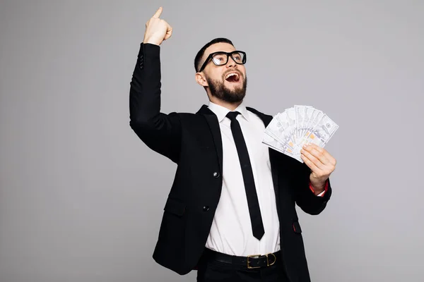 Attraktiver junger Geschäftsmann mit Lächeln, das Geld in der Hand hält und auf weißem Hintergrund zeigt — Stockfoto