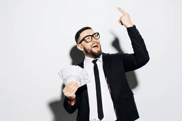 Hombre gritando en traje oficial con dinero en efectivo en las manos y señaló de pie aislado sobre fondo de pared gris . — Foto de Stock