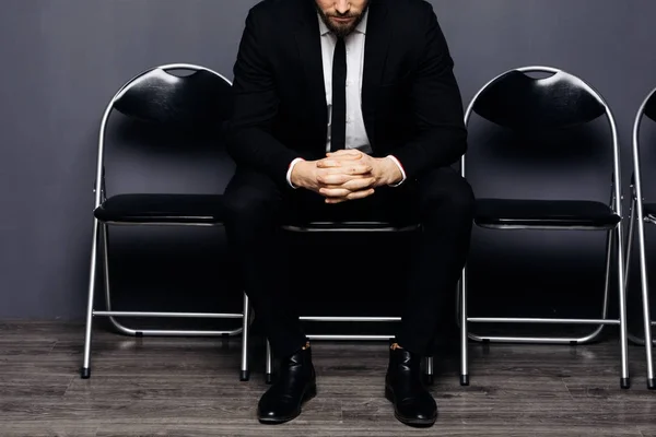 Close up of crossed hands of Young handsome man sitting on chair and waiting for his turn in office hall — Stock Photo, Image
